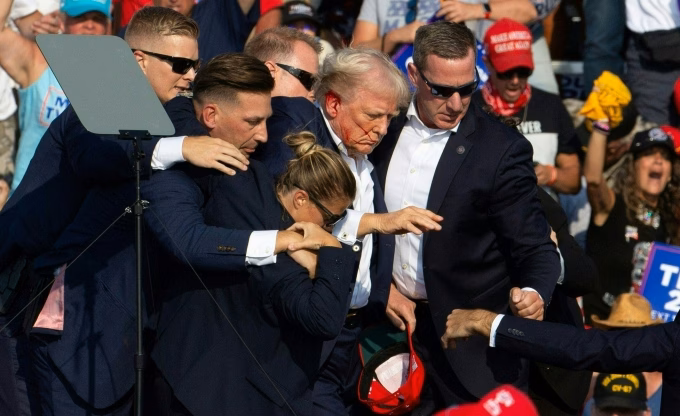Cựu tổng thống Mỹ Donald Trump với gương mặt đầy máu khi được mật vụ đưa khỏi sân khấu sau vụ ám sát hụt ở Butler, Pennsylvania ngày 13/7/2024. Ảnh: AFP